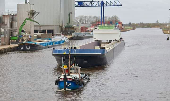 Sleepboot Metje assisteert een groot binnenvaartschip in een kanaal bij een overslagkade