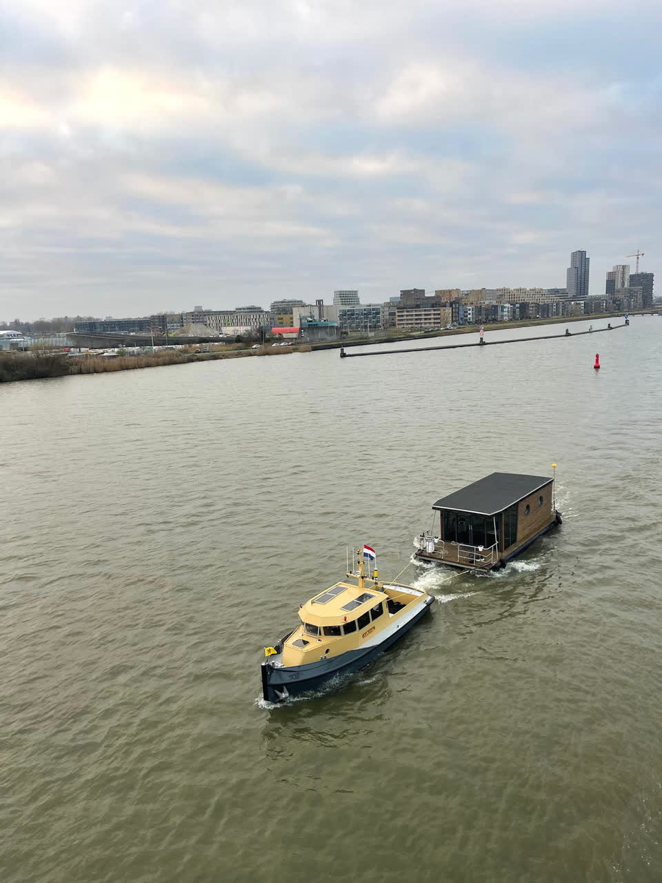 Sleepboot Narwhal sleept een drijvende woning over het IJ bij Amsterdam