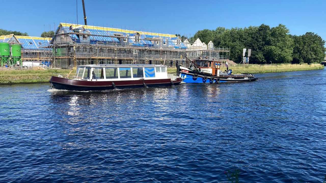Salonboot wordt langszij gesleept langs een bouwplaats aan het water